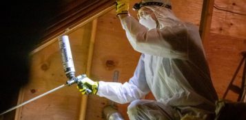 A man dressed in a white suit and gloves works on insulation, highlighting HomeWorks Energy's collaboration with Mass Save for home upgrades.